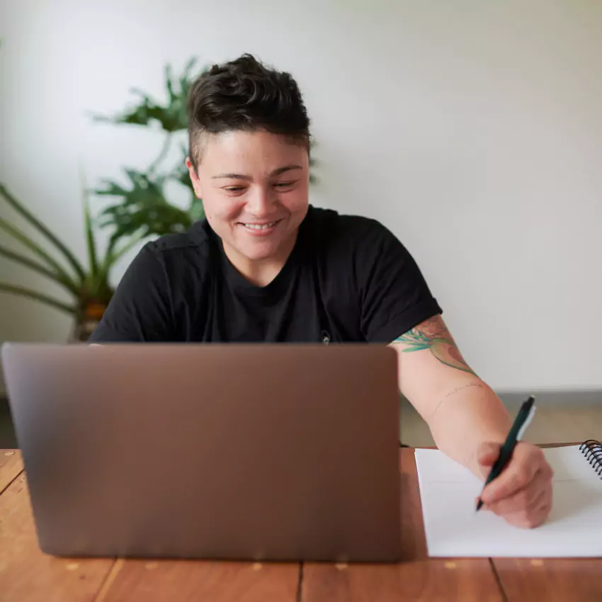 gender neutral person-short-hair-smiling-laptop