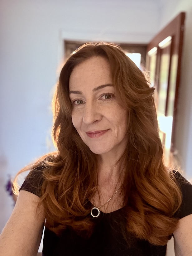 48 year old red headed woman smiling at the camera