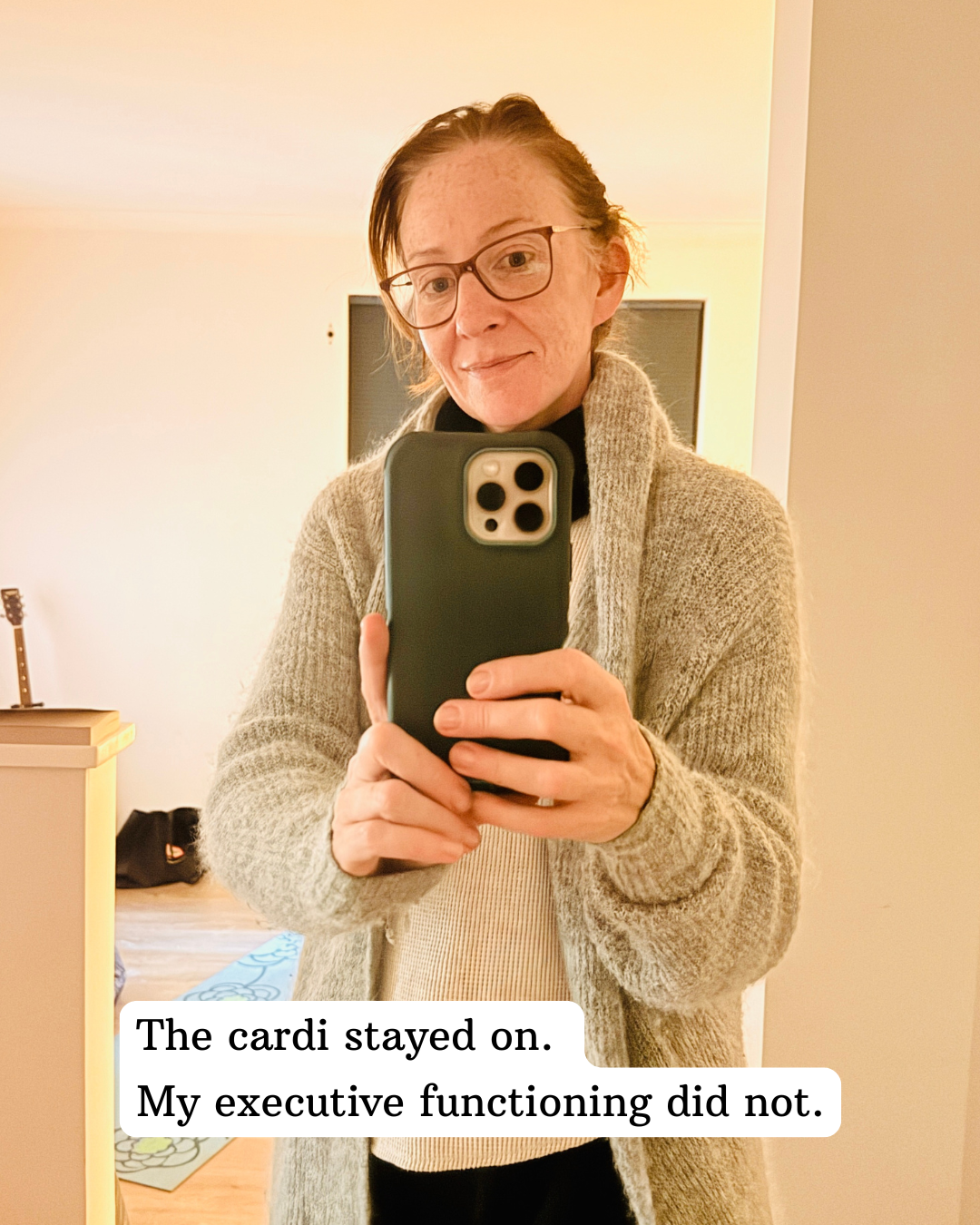 Red head woman taking a selfy. She is wearing a wooly grey cardigan that has been itching her all day. She has refused to take it off.